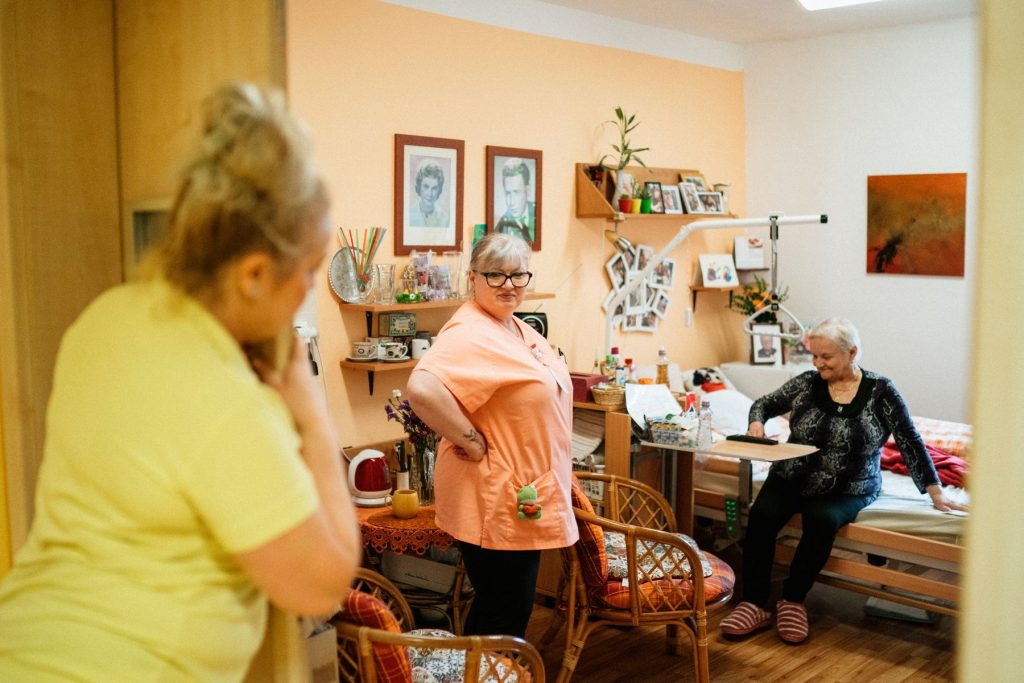 Pflegekraft betreut eine Bewohnerin in ihrem Zimmer im Seniorenheim